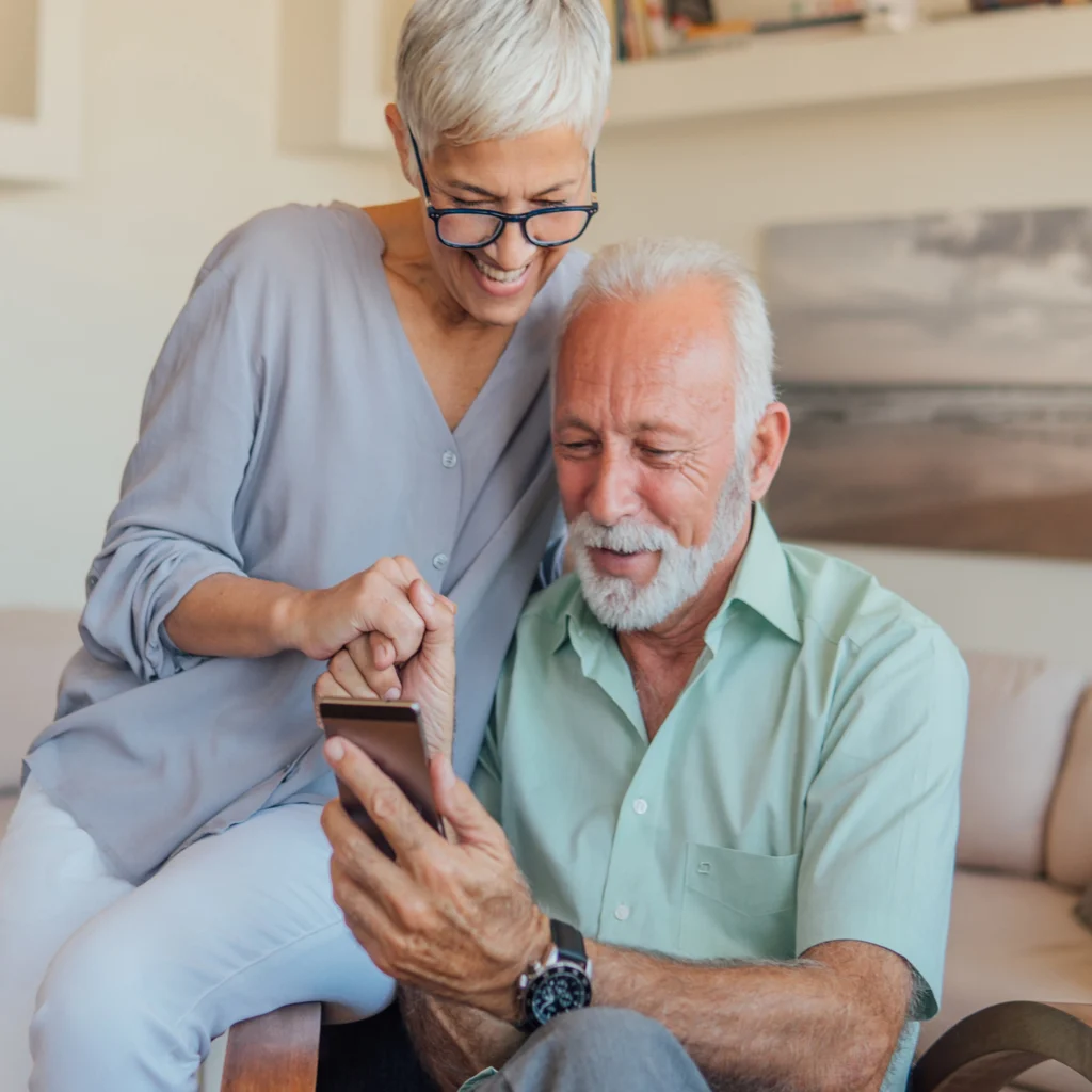 A patient and their partner sitting together at home, looking at the Kneu app on a phone
